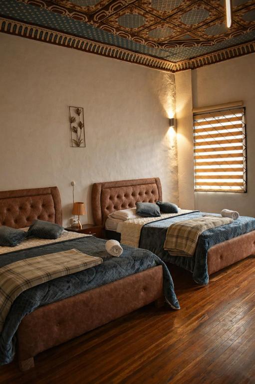 a bedroom with two beds and a window at Suite Colonial Patrimonio UNESCO Centro Histórico Cuenca in Cuenca