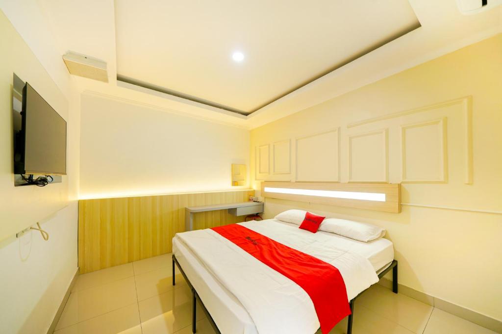 a bedroom with a bed with a red and white blanket at JM Tuparev Mitra RedDoorz in Karawang