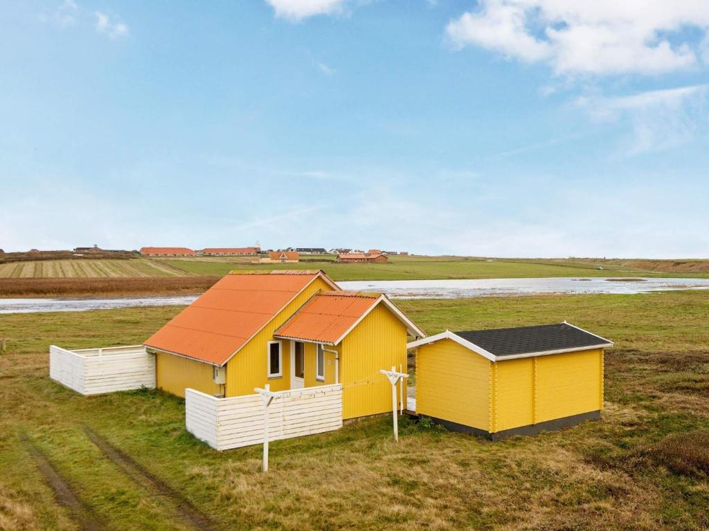a yellow house with a red roof in a field at 4 person holiday home in Lemvig in Lemvig
