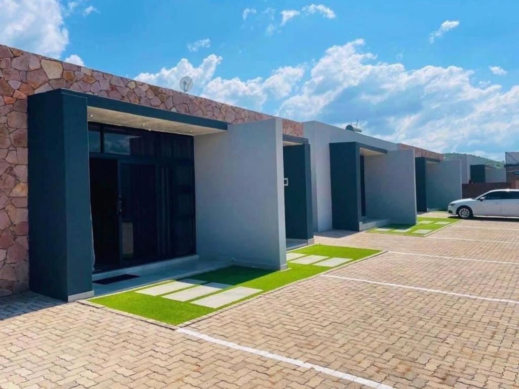 a building with a car parked in a parking lot at MRF Lodge in Louis Trichardt