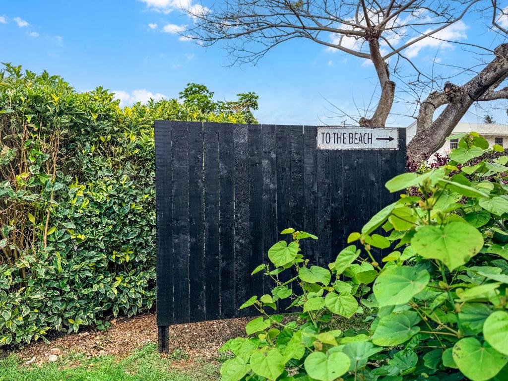 a sign that says to the left next to a bush at Coral Wave Cottage in Waialua