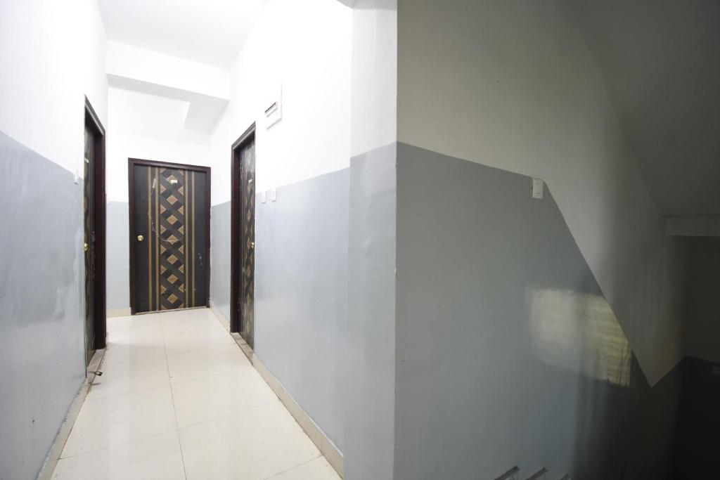 a hallway with white walls and a black door at OYO 82026 BANGUR INN in Nager Bazaar