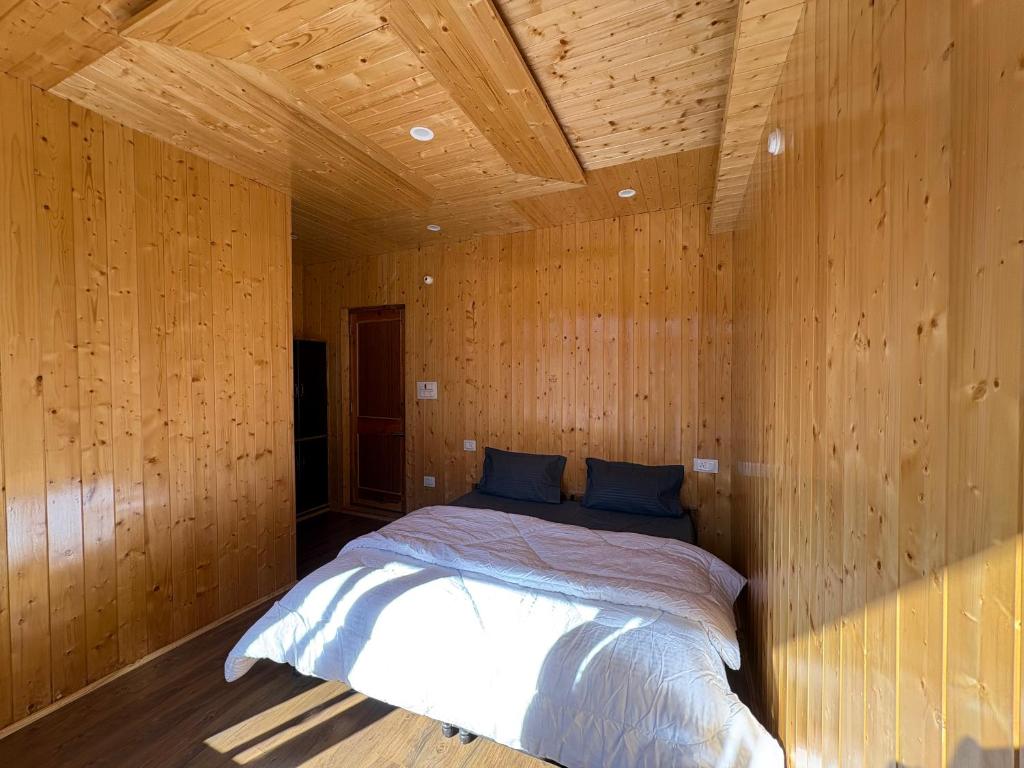a bedroom with a bed in a wooden room at Shubham homestay in Sissu