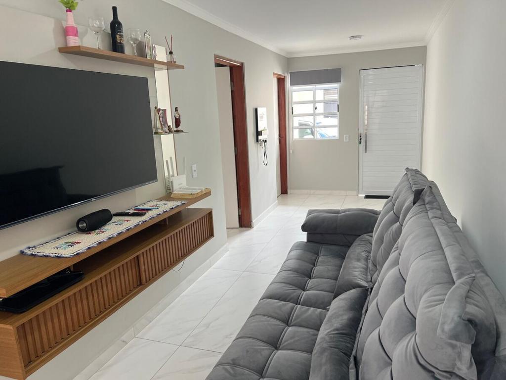 a living room with a couch and a flat screen tv at Casa Sonho Meu in Joanópolis