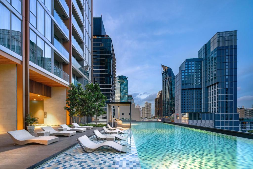 a swimming pool with lounge chairs and a city skyline at Oakwood Suites Bangkok in Bangkok