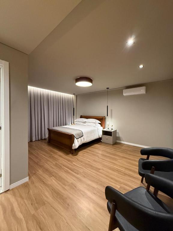 a bedroom with a bed and a chair at Suite Boutique 101 Cheia de Graca in Divinópolis