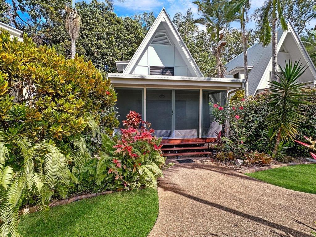 a house with a porch with flowers and plants at Canopy Chalet 6 in Nelly Bay
