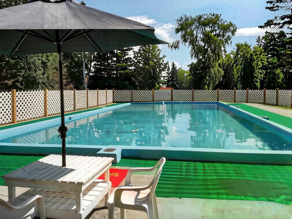 a swimming pool with a table and an umbrella at Auberge La Coudriere (Cool Hotel) in L'Isle-aux-Coudres