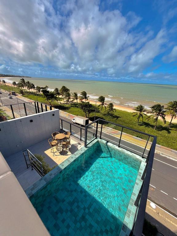 a swimming pool on a balcony with a view of the beach at Compacto Flat na Orla de Intermares in Cabedelo