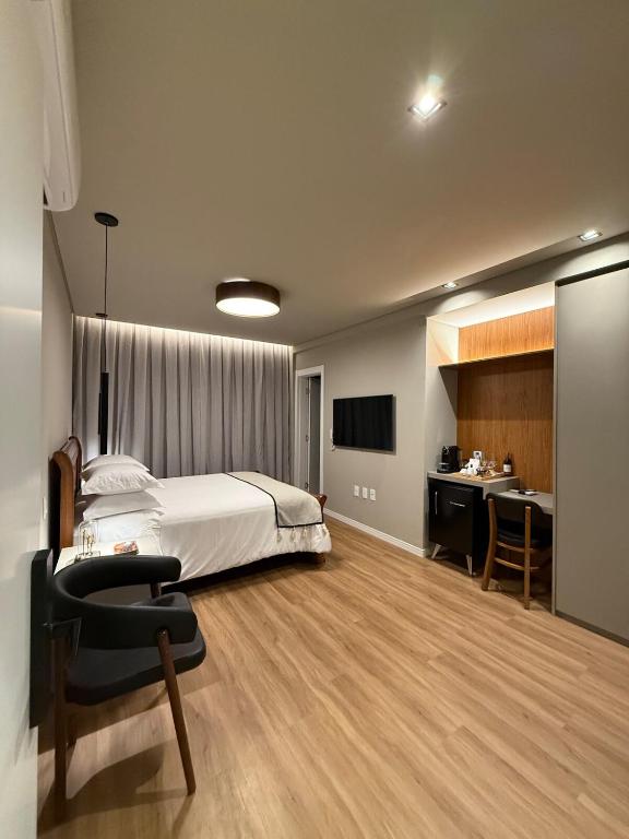 a bedroom with a bed and a desk and a sink at Suite Boutique 102 Cheia de Graça in Divinópolis