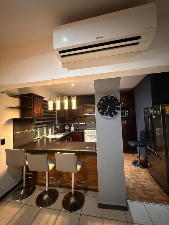 a kitchen with a clock and a counter with chairs at Casa en Tepic in Tepic