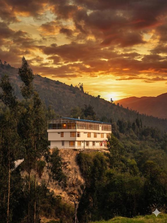 a building on the side of a hill with the sunset at Hotel Alta Montaña Mongui By Seres Viajeros in Monguí