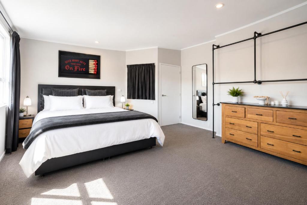 a bedroom with a large bed and a dresser at The Nelson Lookout - Mountain Views & City Centre Living in Nelson