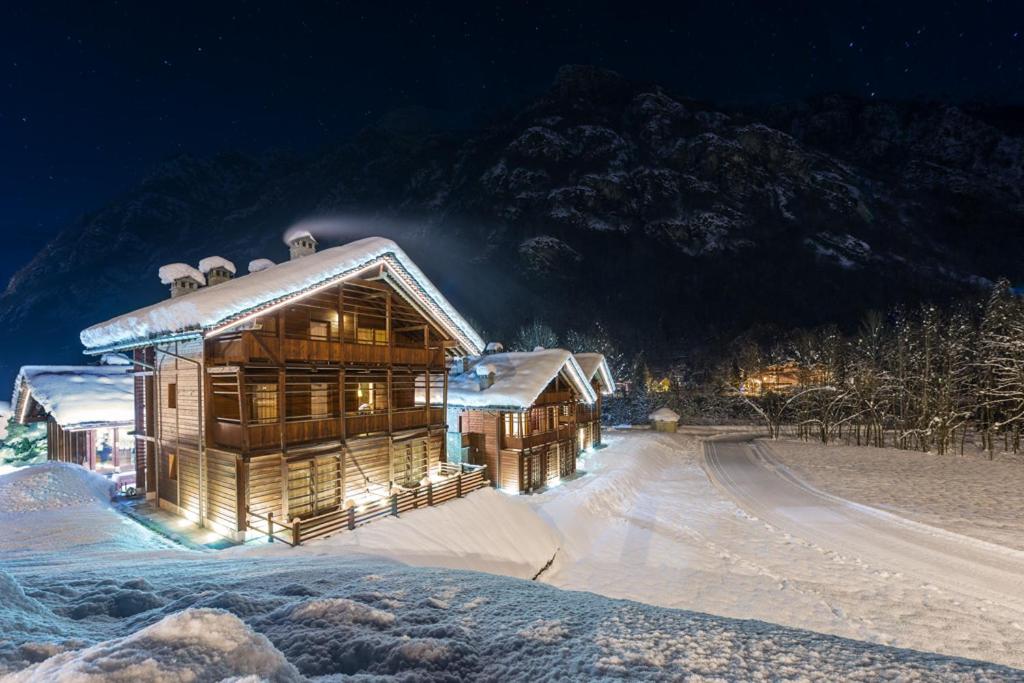 una cabaña de madera en la nieve por la noche en Pietre Gemelle Resort en Alagna Valsesia