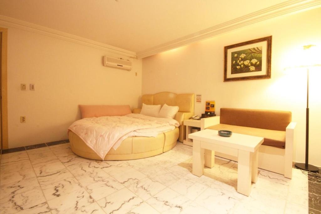 a bedroom with a bed and a table and a couch at 에버그린 모텔 in P'ungnyŏn-gol