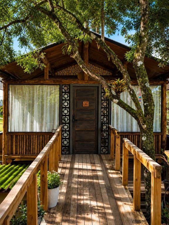 a wooden walkway leading to a house with a tree at Celeiro in Campina Grande do Sul