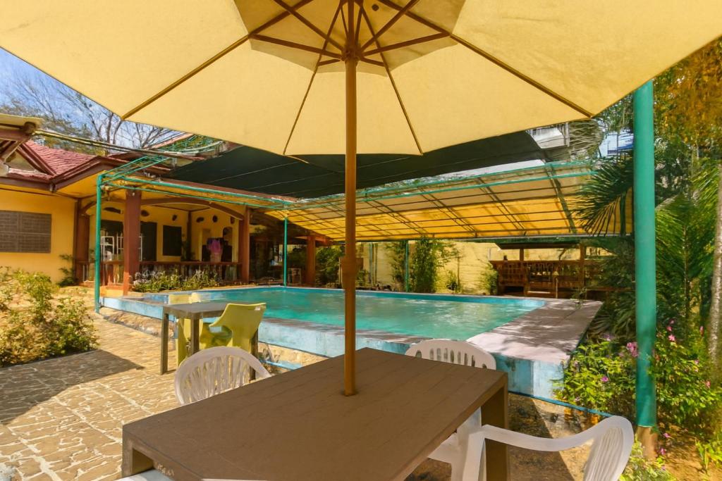 a wooden table with an umbrella next to a pool at Amwani Garden Pool & Kubo in Puerto Princesa City