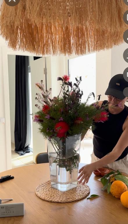a woman arranging a vase of flowers on a table at Casa 26 in Olhão