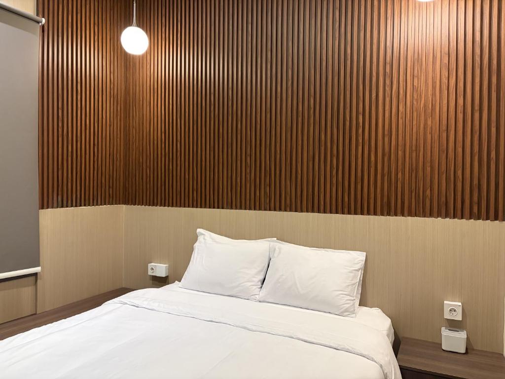 a bedroom with a bed and a wooden wall at Altha Stay Cokro in Ngabean