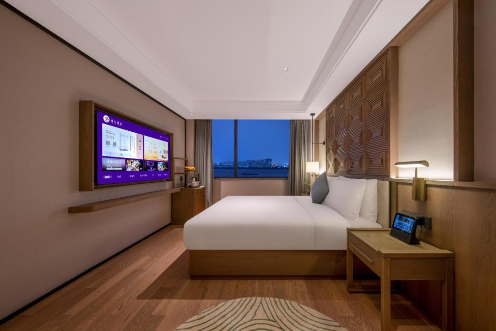 a hotel room with a bed and a tv at Manxin Hotel Nanjing Mufu Mountain in Nanjing