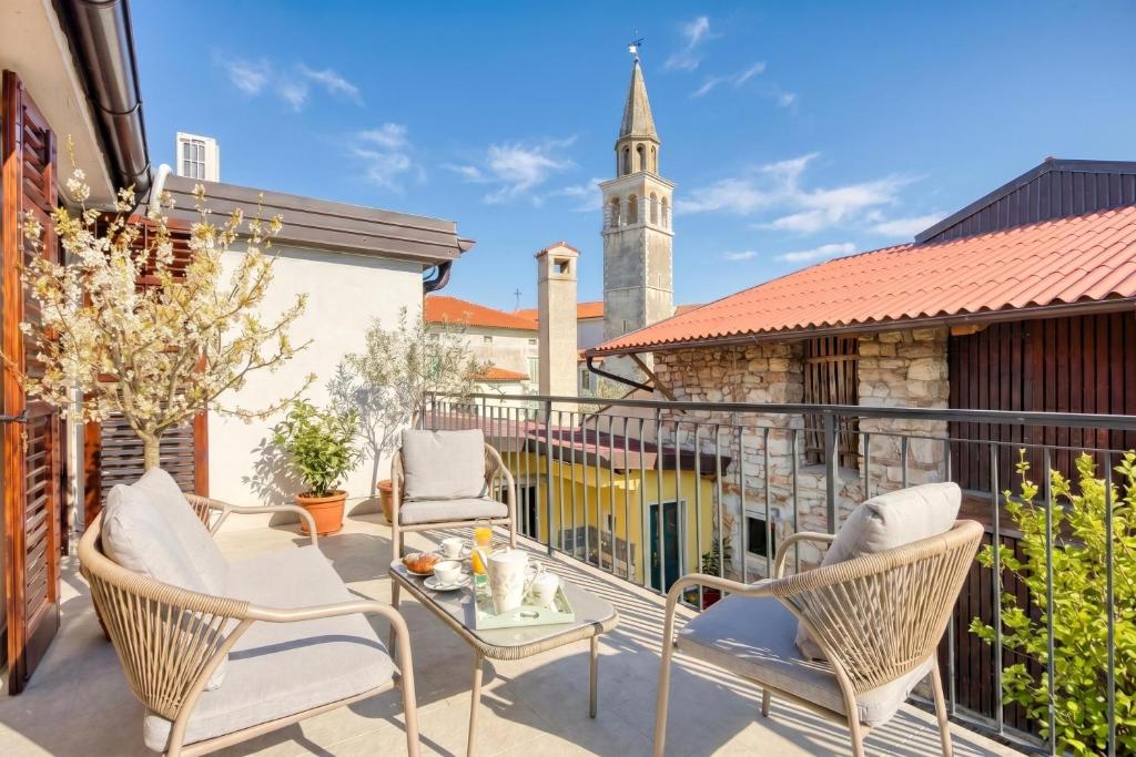 a balcony with chairs and a table and a church at Vila Leonarda with Terrace and Garden - Happy Rentals in Miren