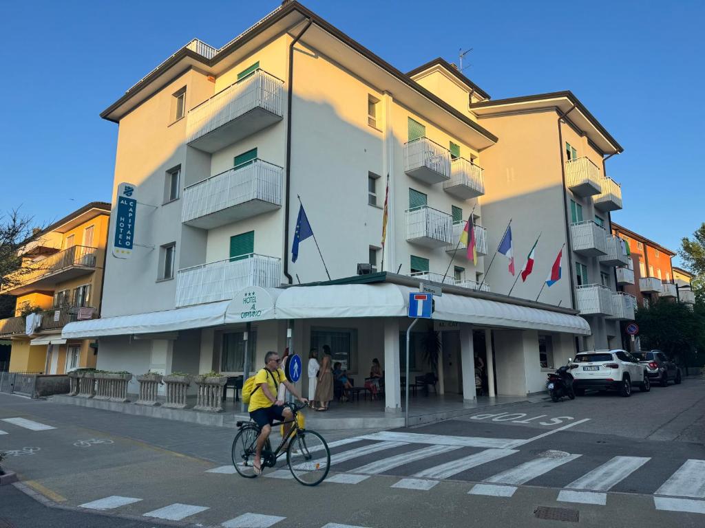 Ein Mann fährt mit dem Fahrrad vor einem Gebäude in der Unterkunft Hotel Al Capitano in Caorle