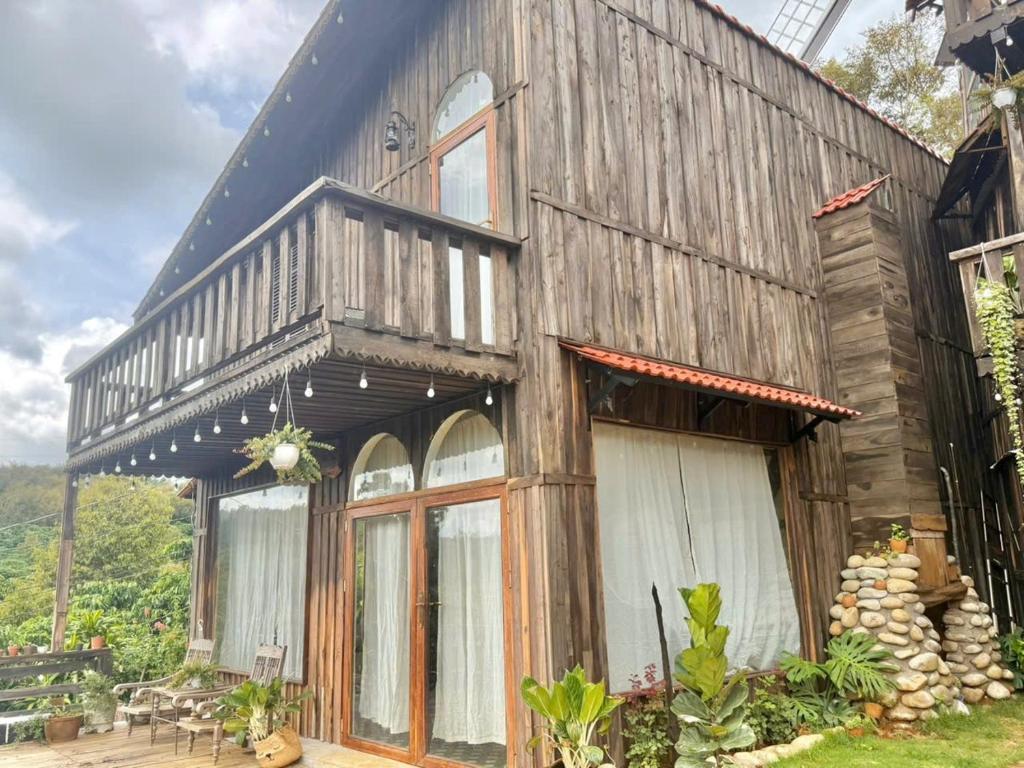 an old wooden house with a balcony on it at Đồi Ông Thoại Cottage in Bảo Lộc