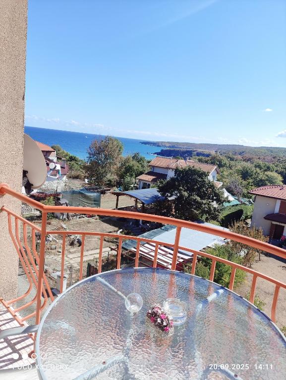 a glass table on a balcony with a view of the ocean at Любимото синьо в Синеморец in Sinemorets
