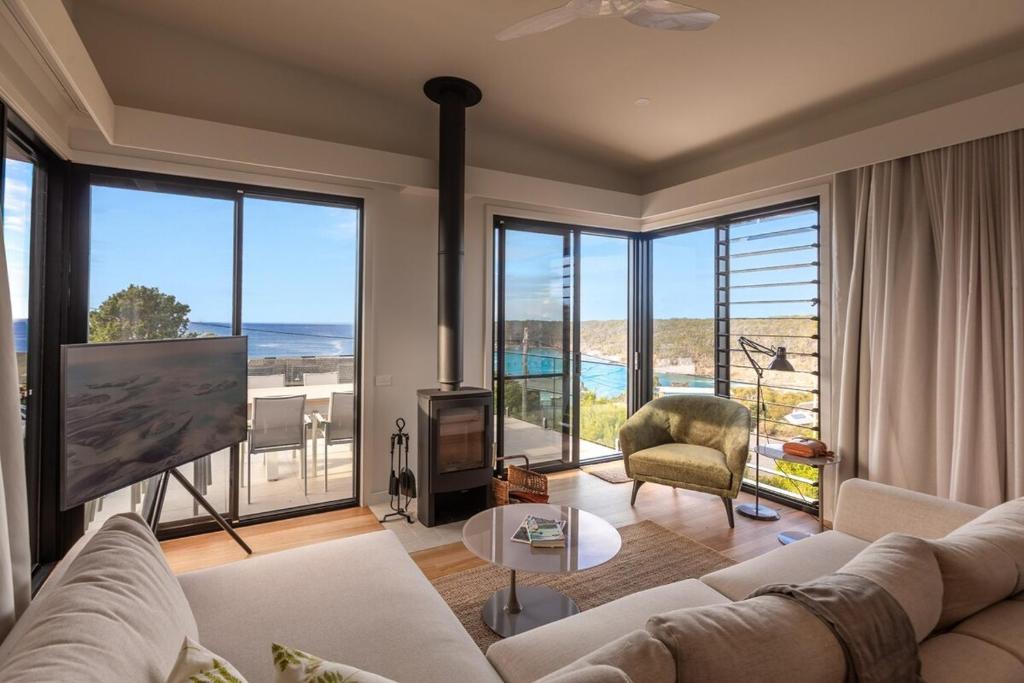 a living room with a couch and a large window at Perfectly Pambula in Pambula Beach