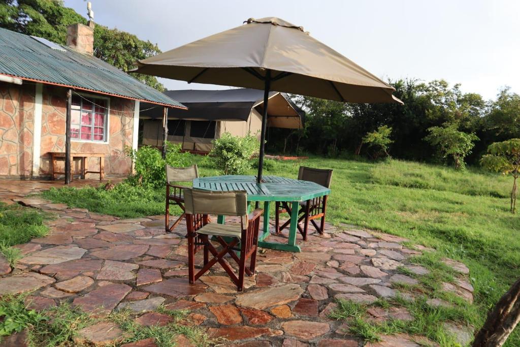 a table and chairs with an umbrella in a yard at Sunshine maasai mara safari camp in Sekenani