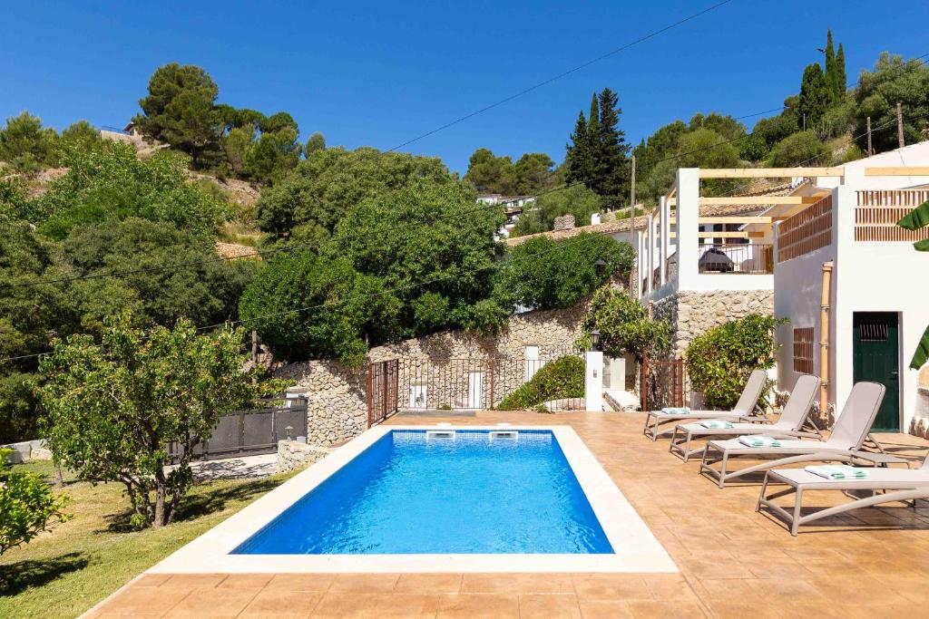 a villa with a swimming pool and lounge chairs at Sa Font in Puigpunyent