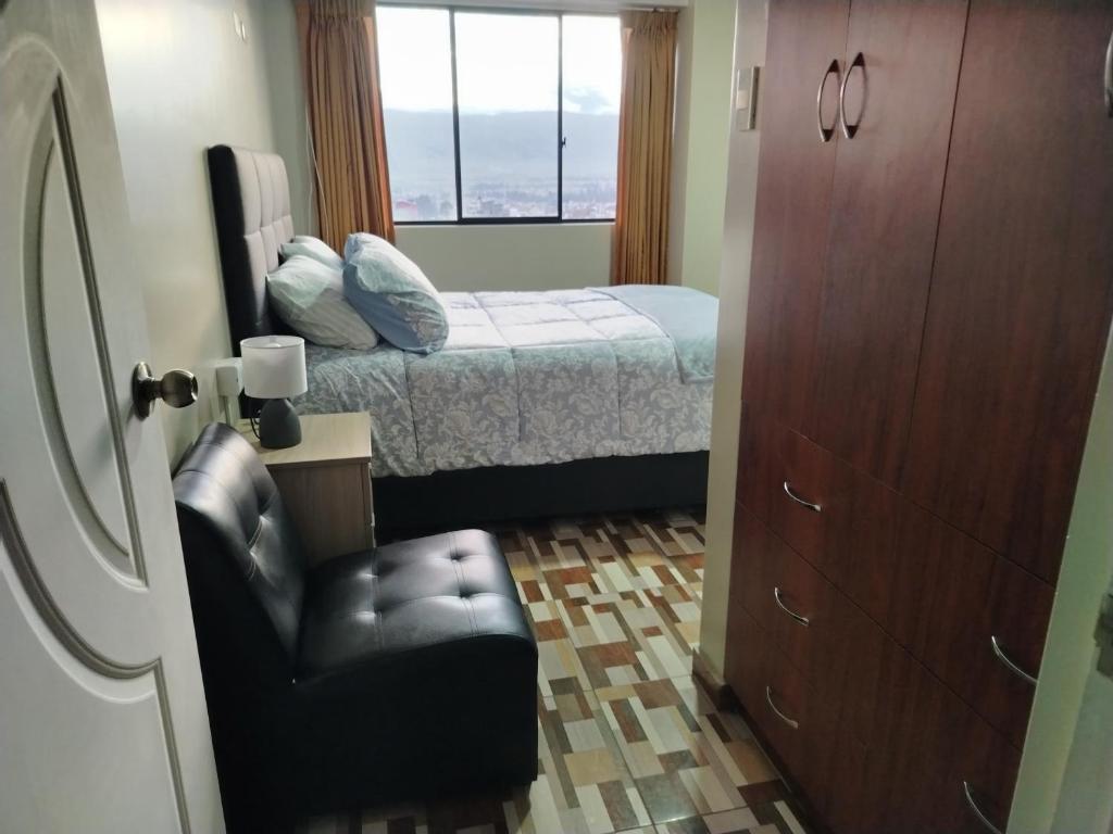 a bedroom with a bed and a chair and a window at Alojamiento Wanka in Huancayo