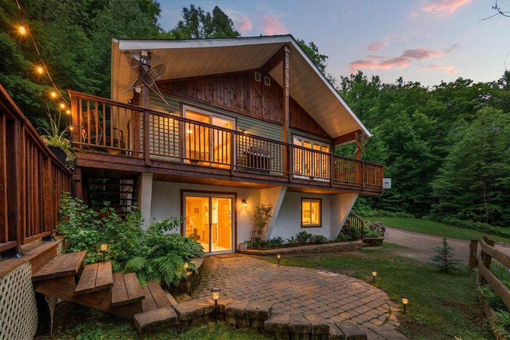 a house with a balcony and a walkway in front at Spa Game room Waterfront - Le Refuge Vert in Brébeuf