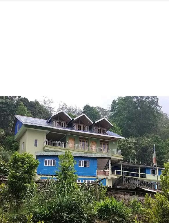 a large house with a blue and white building at Denzongpa Homestay in Takdāh