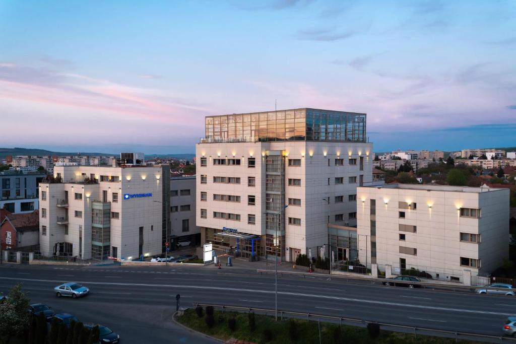 a tall white building with a road in front of it at Wyndham Cluj in Cluj-Napoca