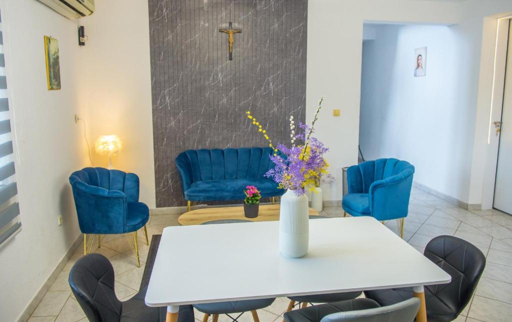 a dining room with a white table and blue chairs at DalEro Sunset Apartments Medjugorje in Međugorje