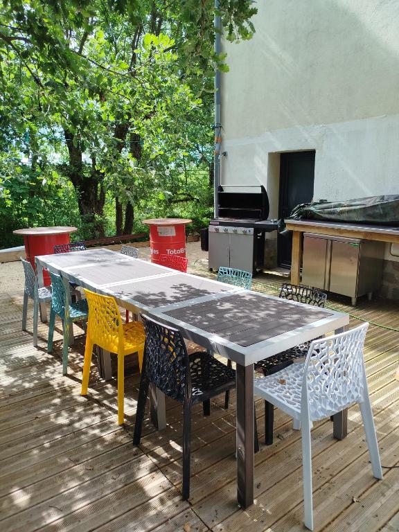 a ping pong table with chairs and a grill at Lénola en Ardèche in Labeaume