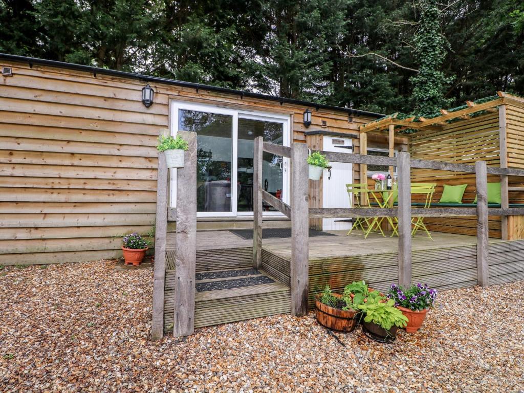 a wooden deck with potted plants and a house at Harvest Lodge in Haywards Heath