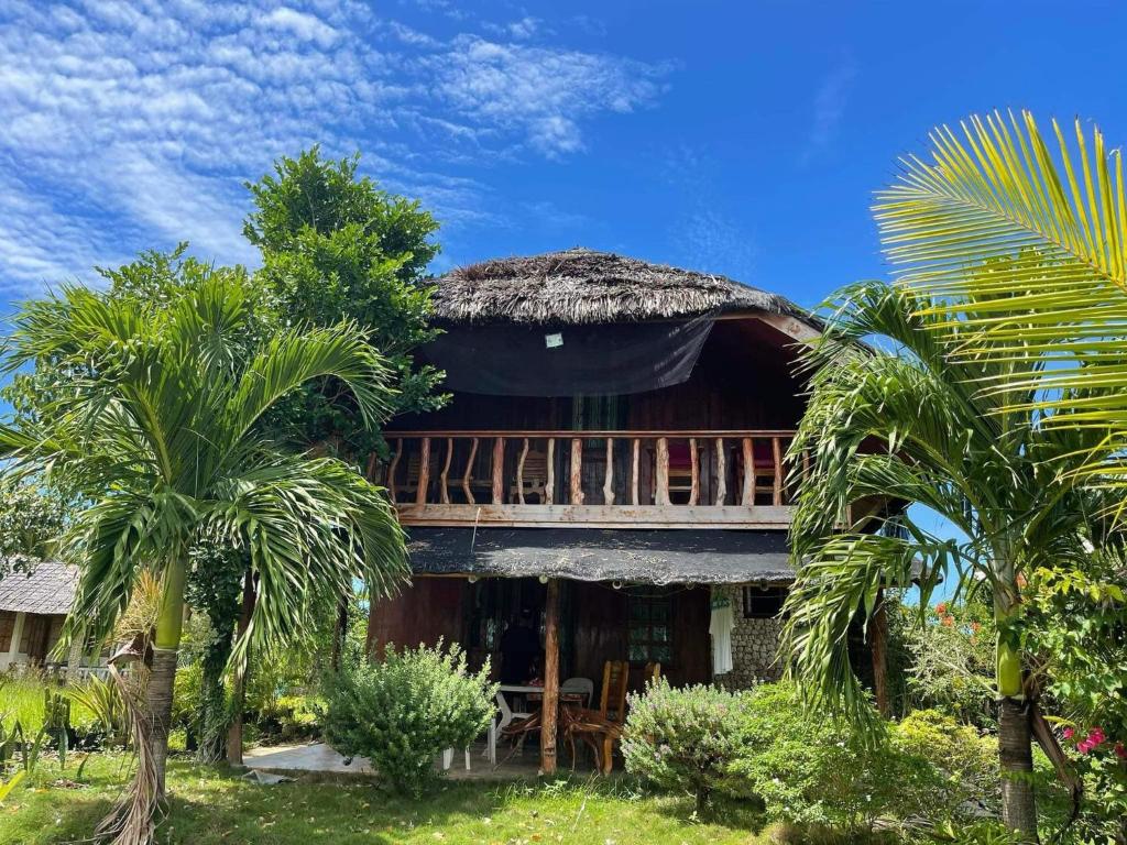atropical house with a thatched roof and palm trees at Sunset Haven in Siquijor