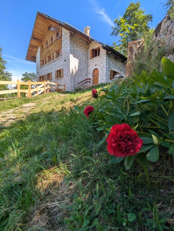 an old house with red flowers in front of it at Chalet Peter in Folgaria