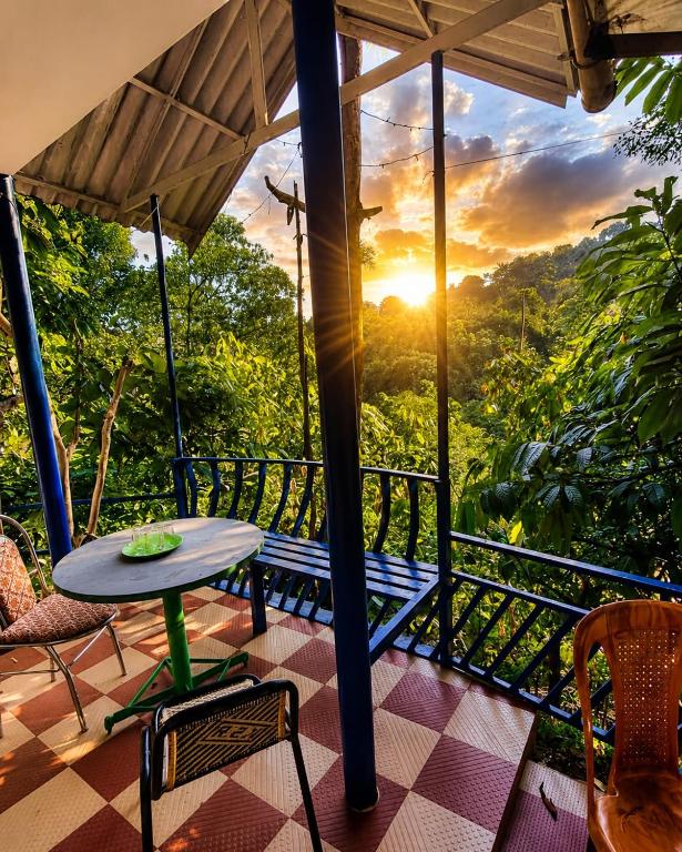 a balcony with a table and chairs and the sunset at munnar Green portico Cottages in Anachal