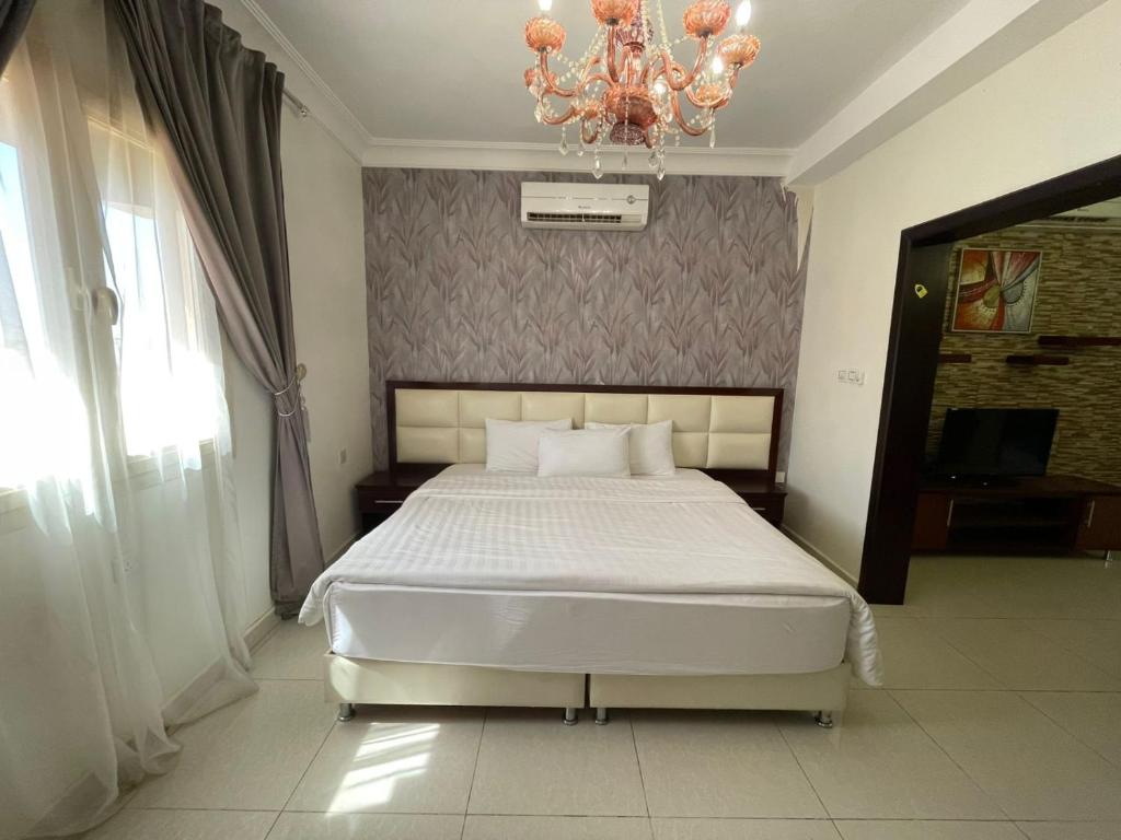 a bedroom with a white bed and a chandelier at فندق قمة البستان الرفاع in Arar