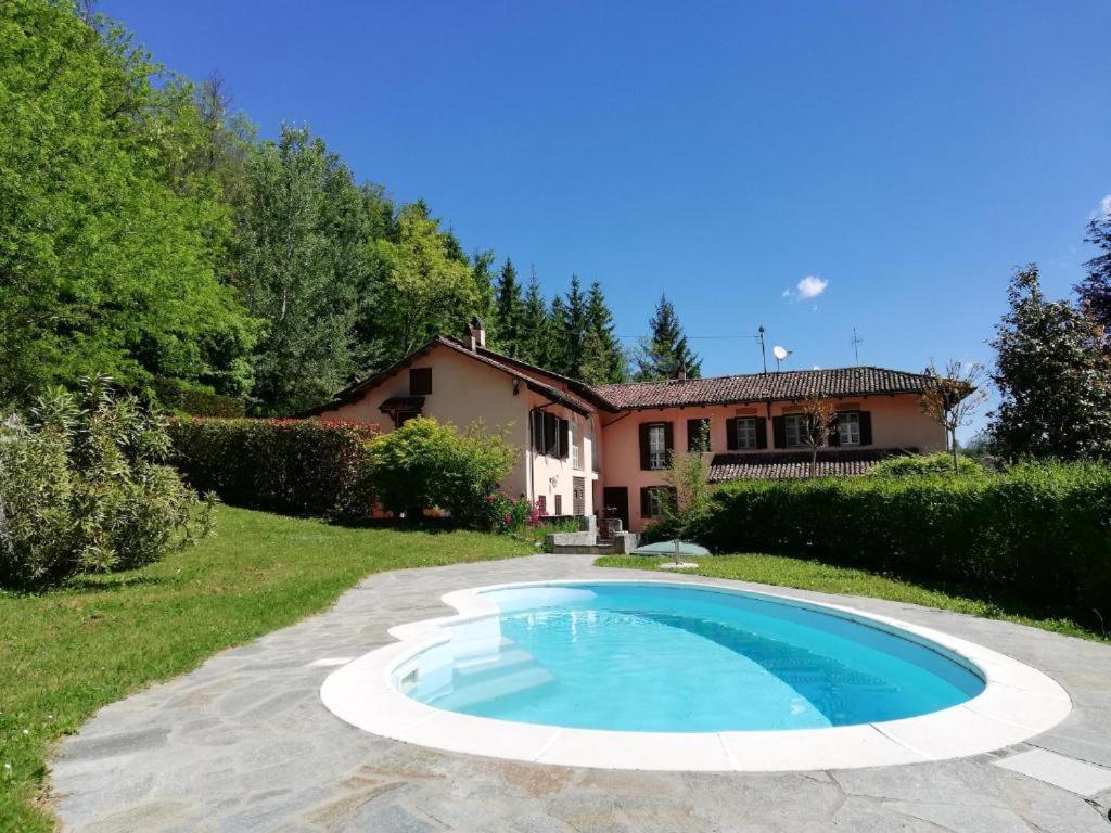 a swimming pool in front of a house at Cascina Bolichin in Diano dʼAlba
