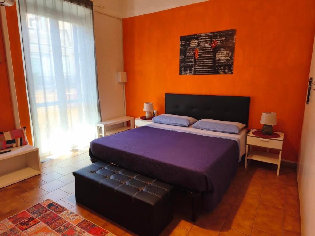 a bedroom with a large bed with an orange wall at Appartamento in centro con terrazza in Viareggio