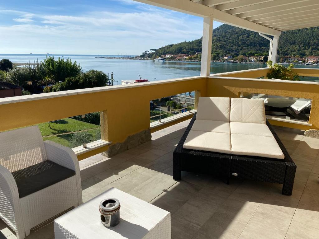 a balcony with a couch and chairs and a view of the water at Maison Del Magra in Ameglia
