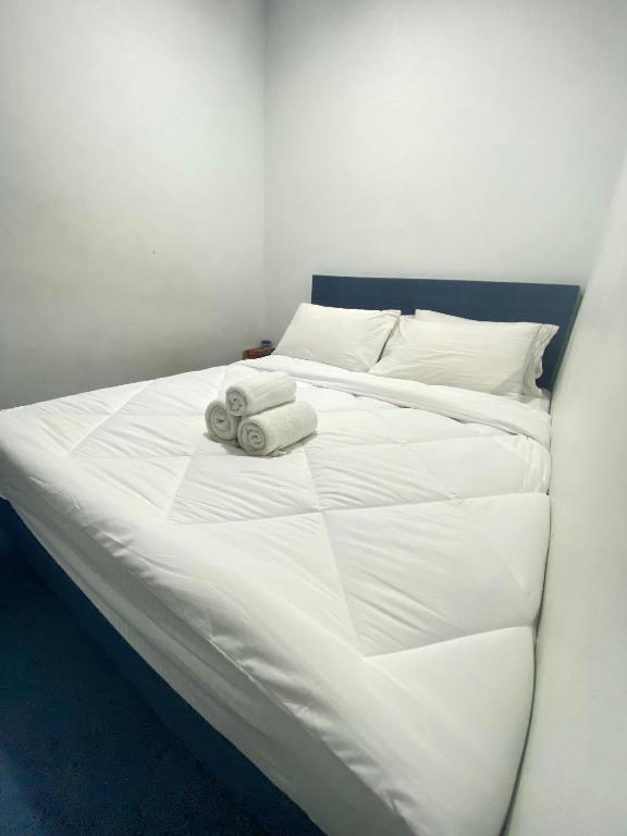 a white bed with two towels on top of it at Enviropath Hotel now Bayan Nur Inn in Kampong Pengkalan