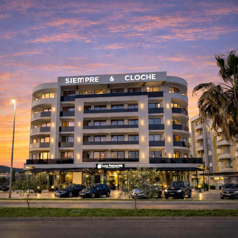 a large building with cars parked in a parking lot at Grand Clochē in Ulcinj