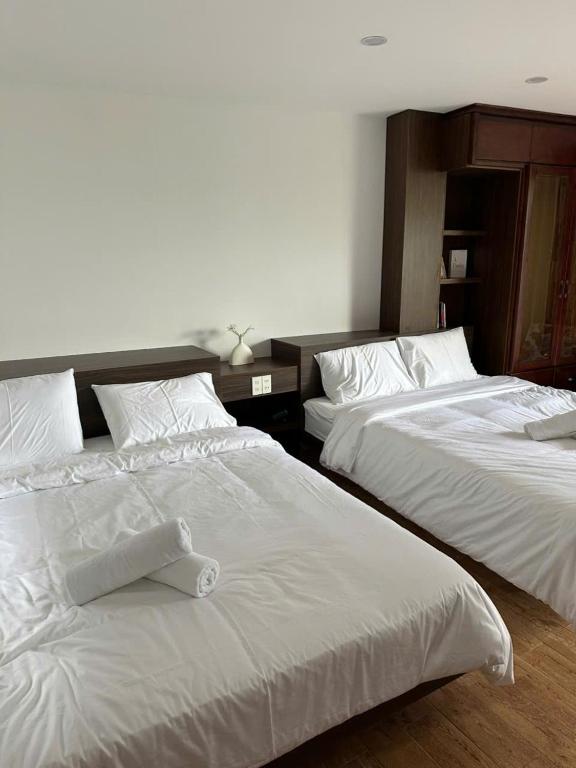 two beds in a hotel room with white sheets at MoChy Homestay in Thôn Trường Giang