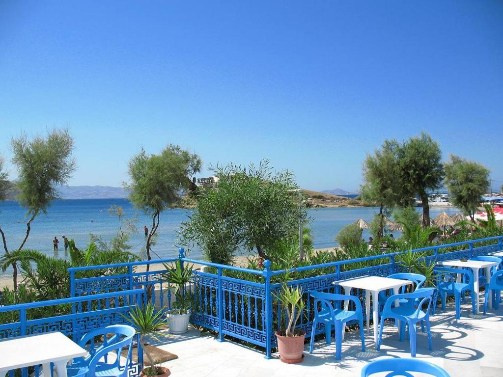a row of blue tables and chairs next to the water at Asteria Hotel in Naxos Chora
