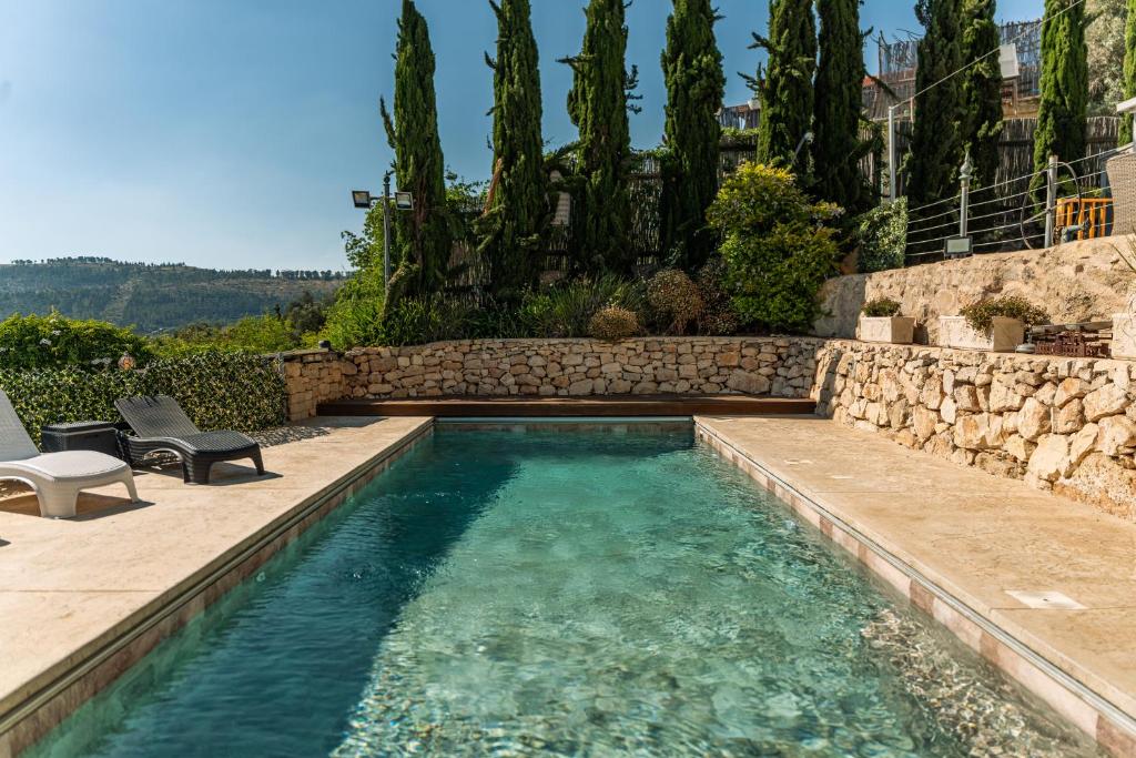 a swimming pool in a yard with a stone wall at עיינות ספיר - Einot Sapir in Sappir